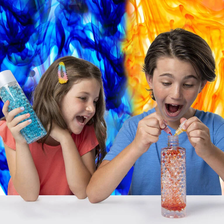 A child is pouring colors in the bottle that is filled with orbeez.